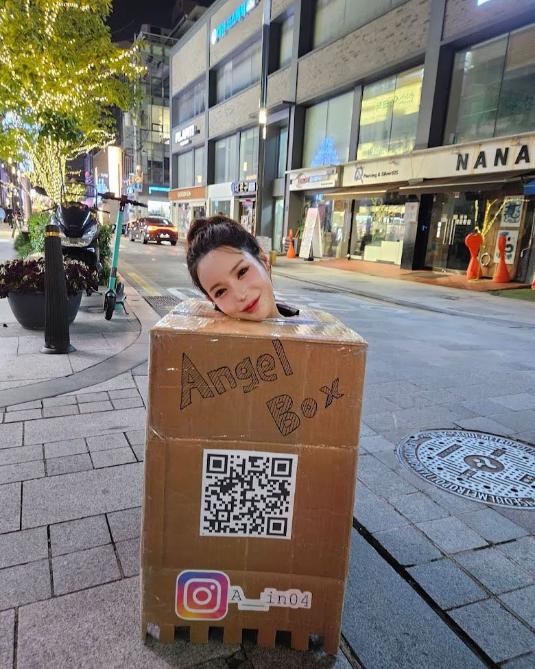 Ah In khoét lỗ trên hộp carton để người khác chạm vào vòng một